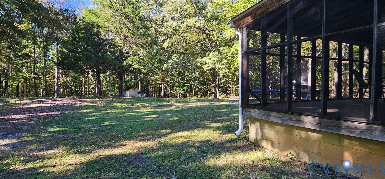 24110 Genito Road, Amelia, VA 23002 Screened porch with a dark frame, concrete block foundation, and exterior yard featuring mature trees and a grassy lawn