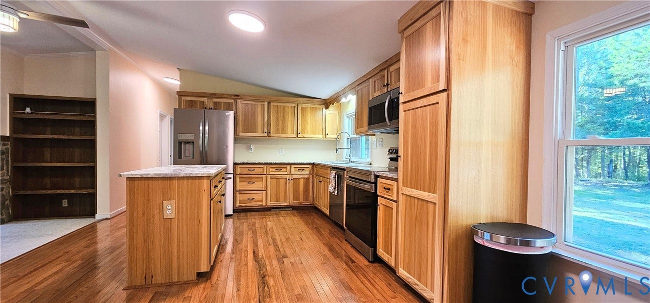 24110 Genito Road, Amelia, VA 23002 Kitchen featuring wood-finish cabinetry, a central island with a stone-surface countertop, stainless steel appliances, wood-finish flooring, and built-in shelving