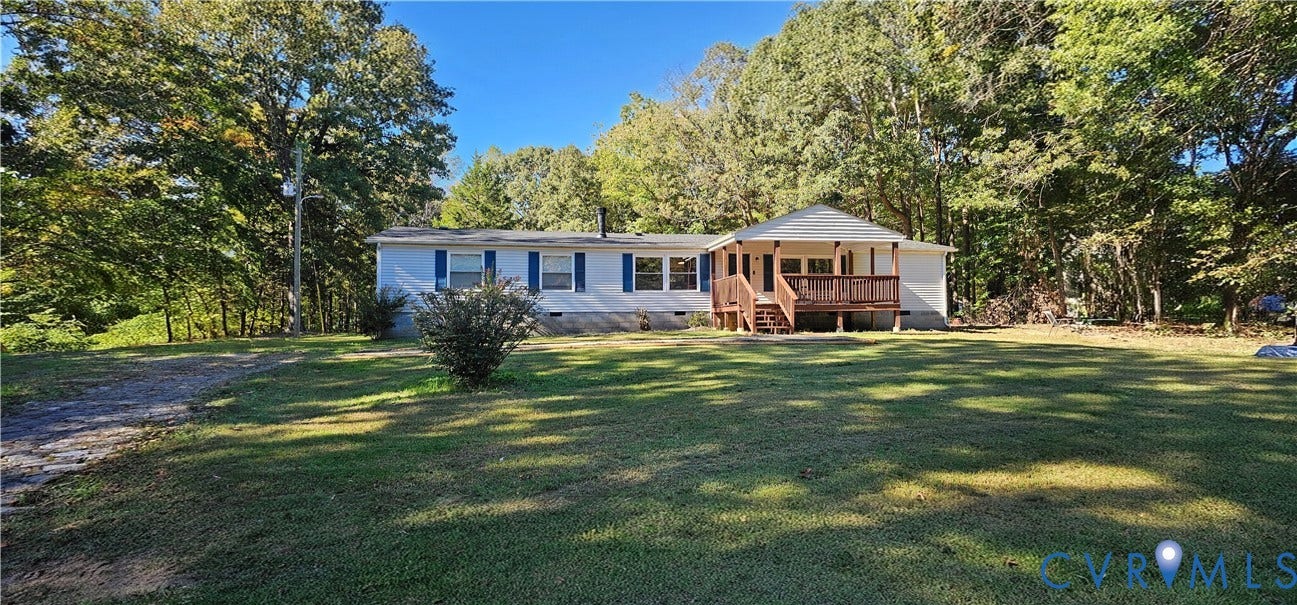 24110 Genito Road, Amelia, VA 23002 Single-story exterior featuring light-toned siding, blue window shutters, a covered wooden front deck, and expansive surrounding grounds with mature trees