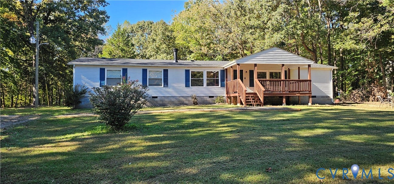 24110 Genito Road, Amelia, VA 23002 Single-story residence featuring light-colored siding, blue window shutters, a covered front porch with wooden railings, and a large yard surrounded by mature trees