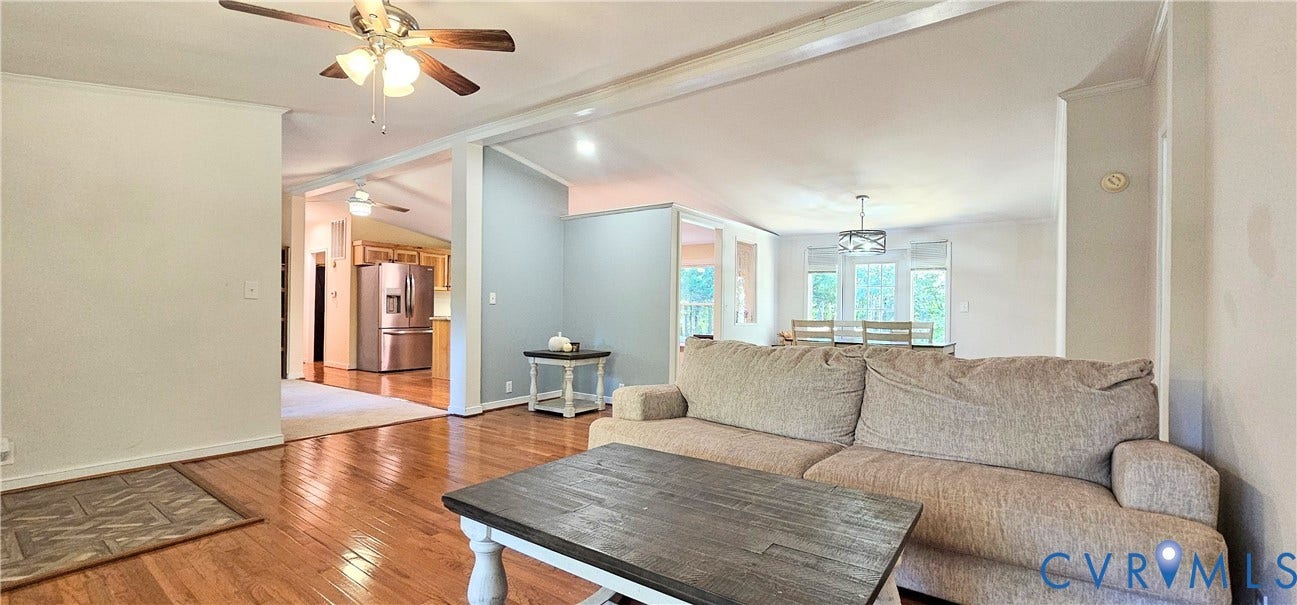 24110 Genito Road, Amelia, VA 23002 Open-concept interior featuring wood-finish flooring, vaulted ceilings, a ceiling fan with integrated lighting, and a multi-light drum chandelier