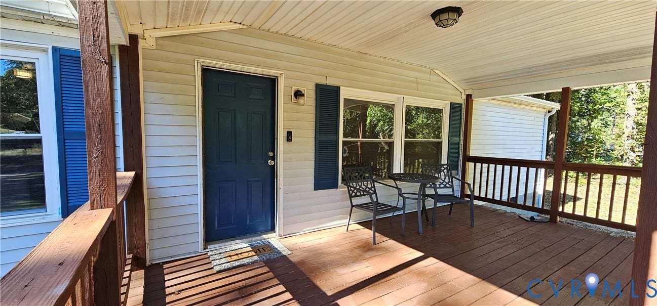 24110 Genito Road, Amelia, VA 23002 Covered porch featuring wood-plank decking, a solid-panel entry door, vinyl siding, and wooden railings