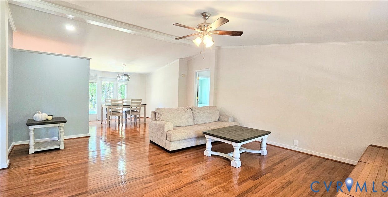 24110 Genito Road, Amelia, VA 23002 Open-concept interior featuring wood-finish flooring, a ceiling fan with integrated lighting, an accent wall, and a multi-light chandelier