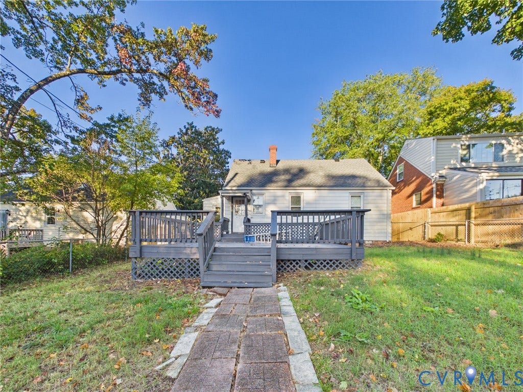 6902 Three Chopt Road, Richmond, VA 23226 Raised rear deck featuring lattice skirting, stone-paver walkway, and mature trees