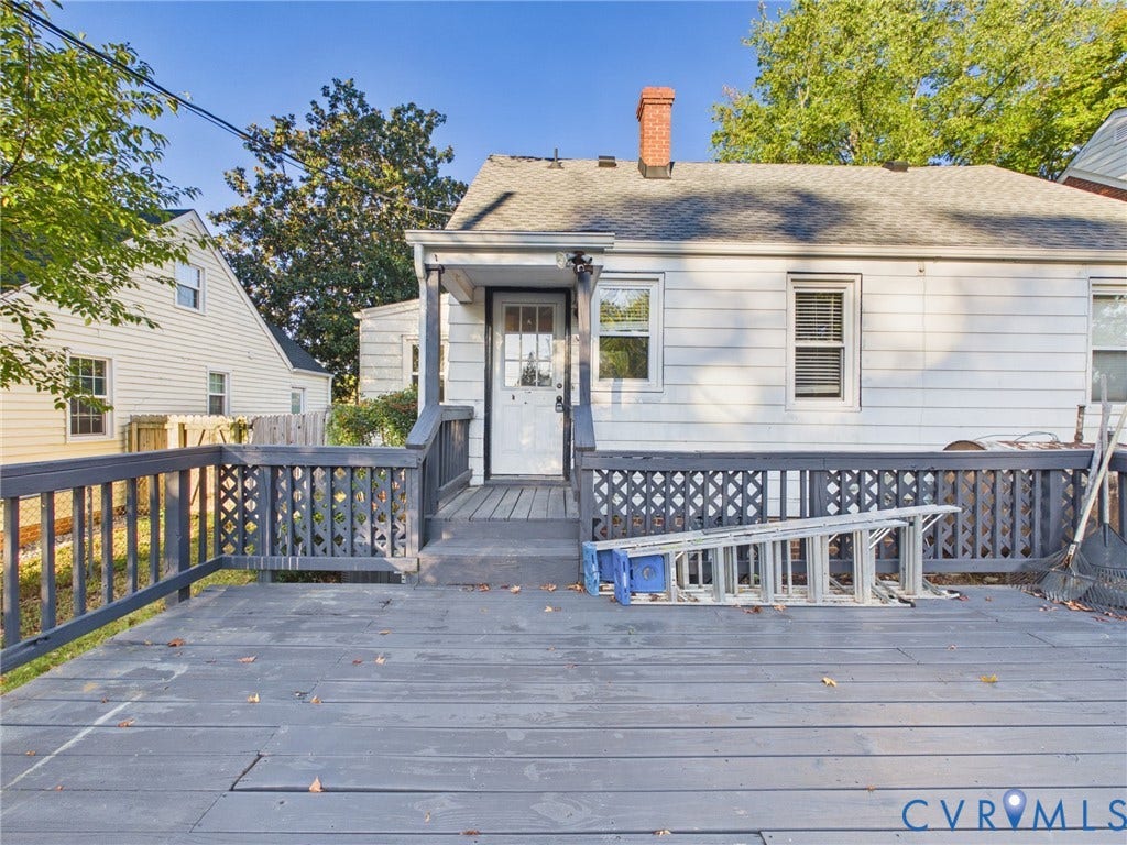 6902 Three Chopt Road, Richmond, VA 23226 Exterior rear elevation featuring white siding, a grey composite deck with lattice railings, a masonry chimney, and multi-pane glass entry door
