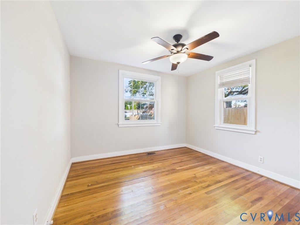 6902 Three Chopt Road, Richmond, VA 23226 Room interior featuring wood-finish flooring, two windows with white trim, and a ceiling fan with integrated lighting