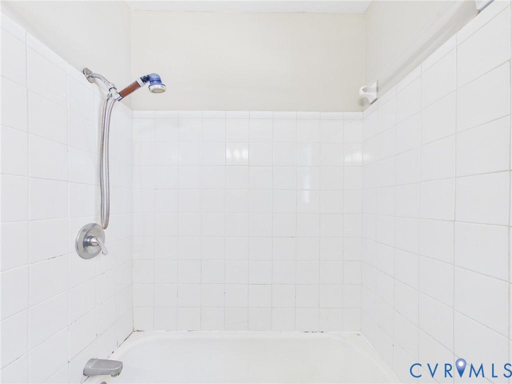 6902 Three Chopt Road, Richmond, VA 23226 Full-height white square-tiled tub surround featuring a chrome-finish single-handle mixing valve, matching tub spout, and adjustable handheld shower head on a slide bar