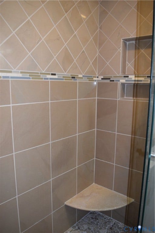 1120 Black Heath Road, Robious/Huguenot, Midlothian, VA 23113 Shower enclosure featuring large-format wall tile, multi-colored glass tile inlay, a corner stone-finish bench, and recessed wall shelving.