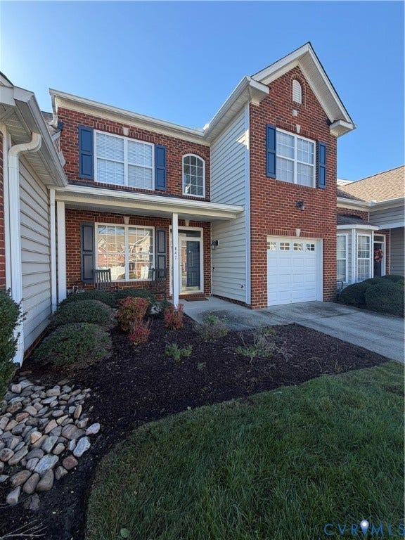 Two-story brick and siding exterior featuring a covered front porch, arched window detailing, and a single-car garage