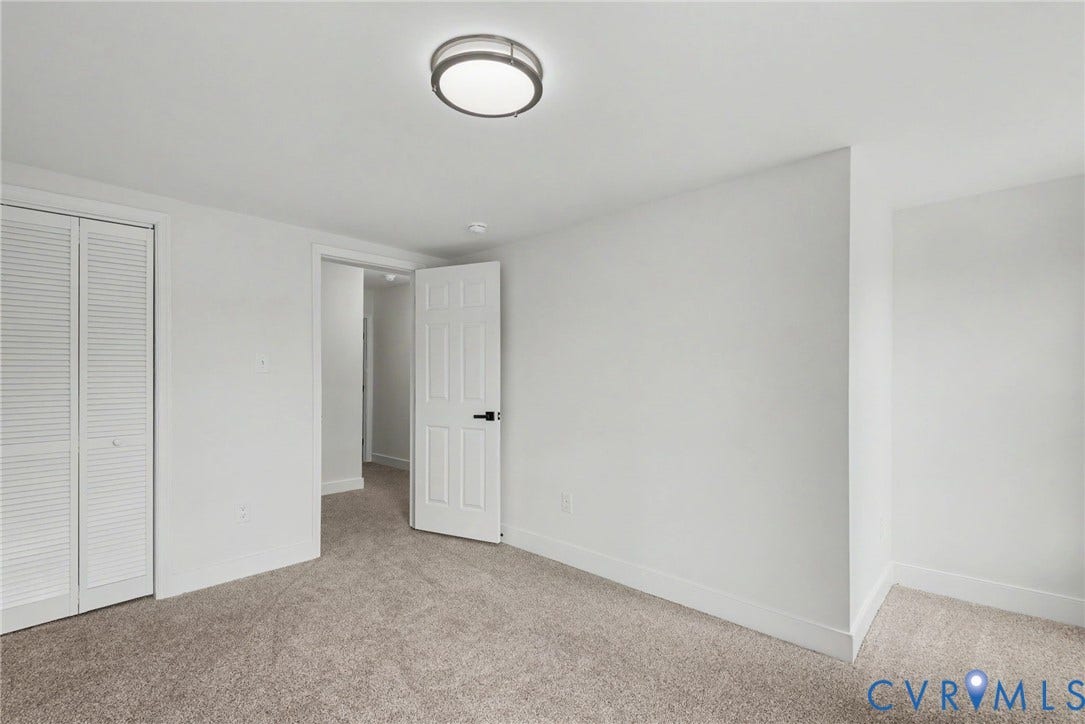1210 N 24th Street, Church Hill Central, Richmond, VA 23223 Room featuring neutral carpeting, a semi-flush mount dome ceiling light, a bi-fold closet door, and a six-panel door with matte black hardware