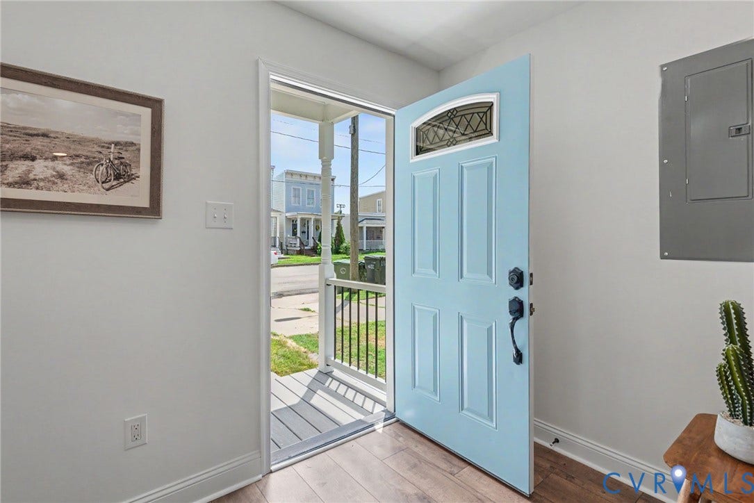 1210 N 24th Street, Church Hill Central, Richmond, VA 23223 Entryway featuring a light blue front door with a decorative arched transom window, wood-finish flooring, and a covered porch with a metal railing