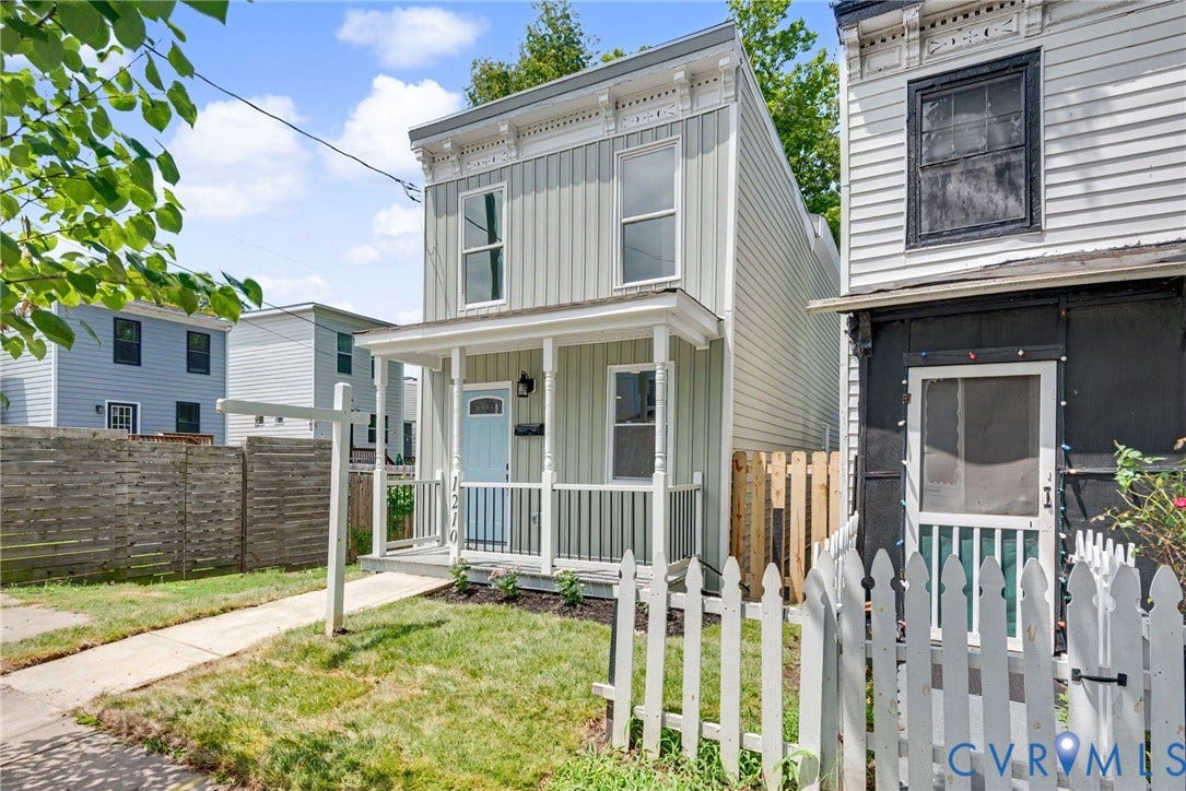 1210 N 24th Street, Church Hill Central, Richmond, VA 23223 Two-story residence featuring vertical siding, decorative roofline corbels, an integrated front porch with turned columns, and a picket-style perimeter fence