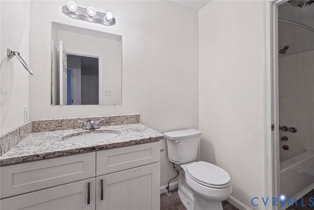 509 Overcliff Court, Walton Park, Midlothian, VA 23114 Bathroom featuring white cabinetry, stone-surface countertop with integrated basin, frameless wall-mounted mirror, three-light vanity fixture, and wood-finish flooring