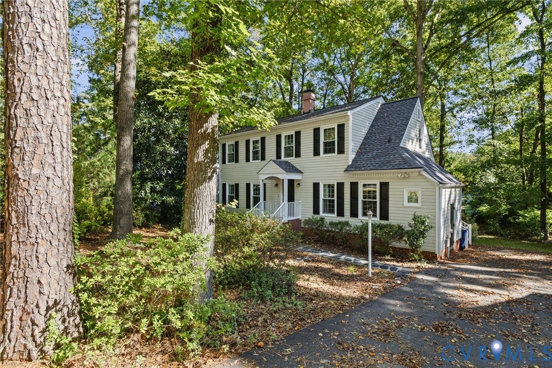 509 Overcliff Court, Walton Park, Midlothian, VA 23114 Two-story colonial-style residence featuring light-toned horizontal siding, dark decorative shutters, a gabled front entryway, a steep-pitched roof, and mature perimeter trees