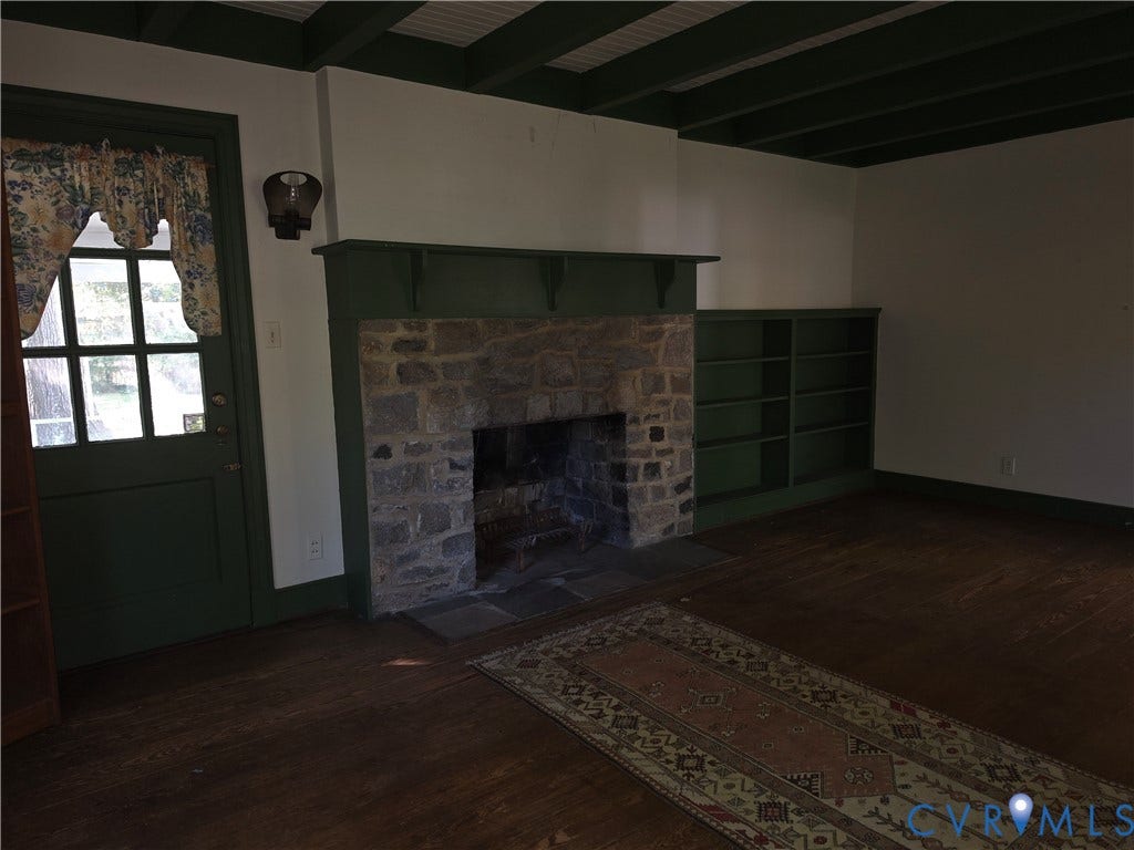 4114 Crestwood Road, Established, Richmond, VA 23227 Stone fireplace with a mantle, built-in shelving, exposed ceiling beams, wood-finish flooring, and a multi-pane glass door