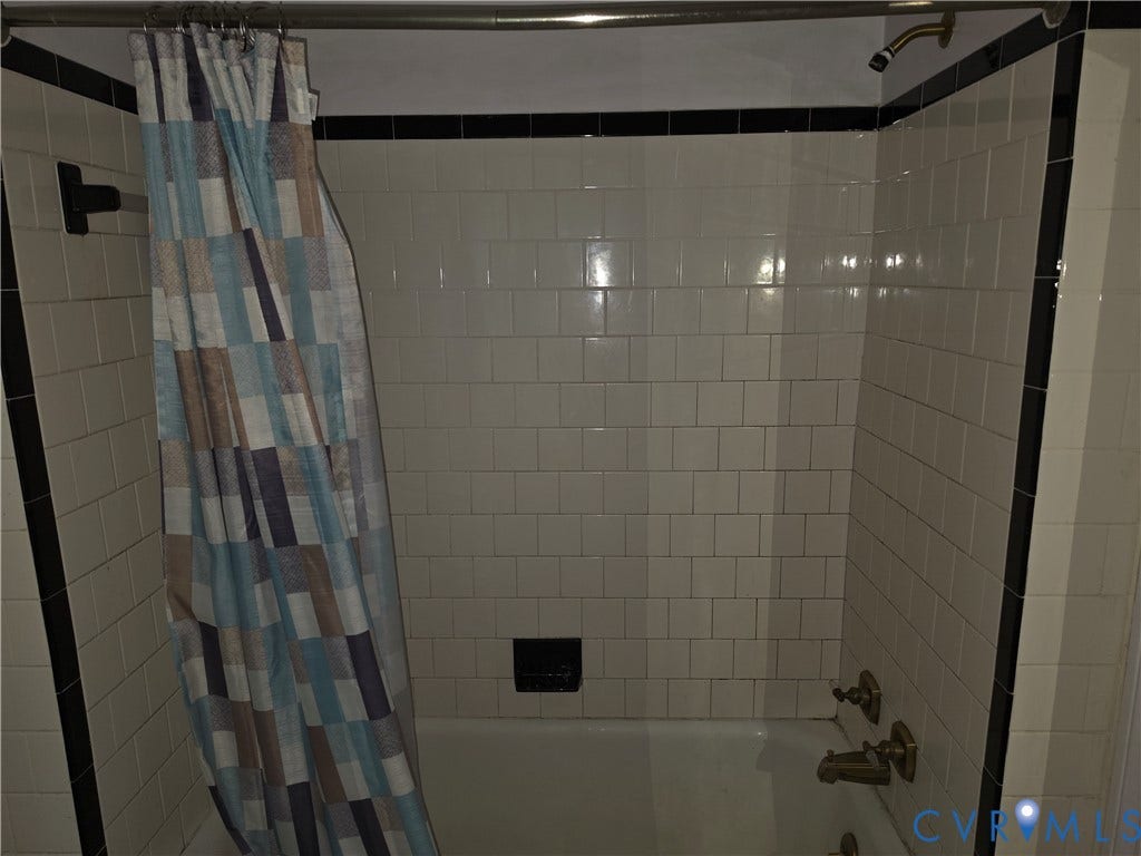 4114 Crestwood Road, Established, Richmond, VA 23227 Shower and tub combination featuring cream-colored wall tiles, a contrasting black accent tile border, and metallic fixtures