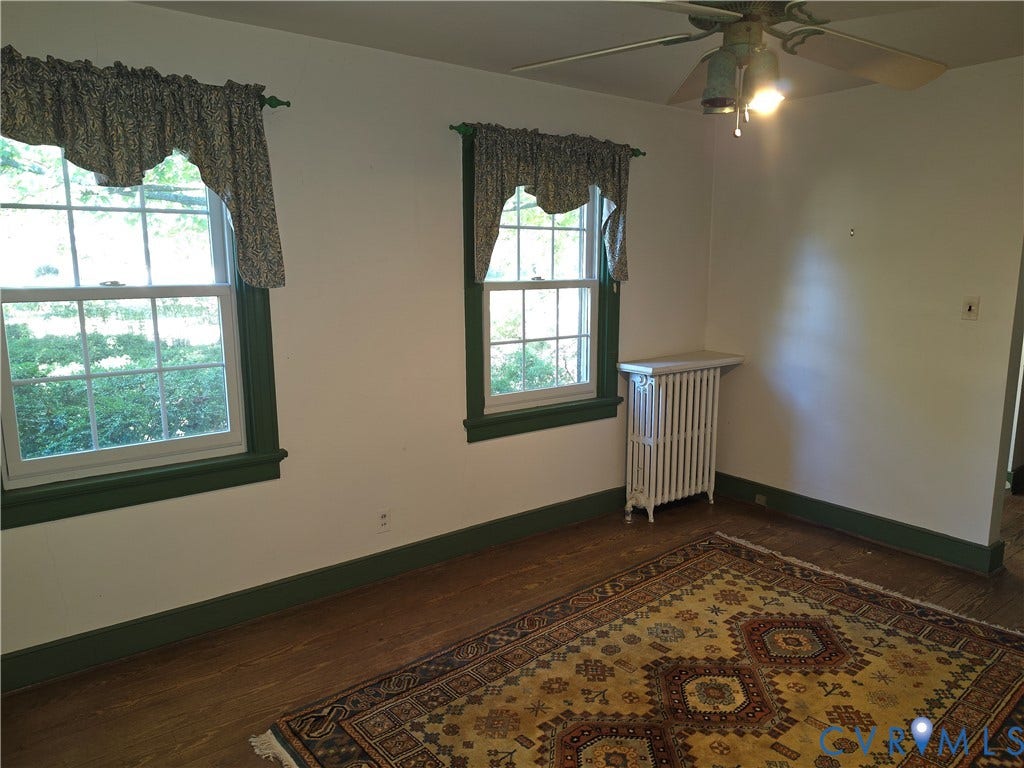 4114 Crestwood Road, Established, Richmond, VA 23227 Interior space featuring hardwood flooring, multi-pane windows with colored casings, and a vertical cast-iron radiator