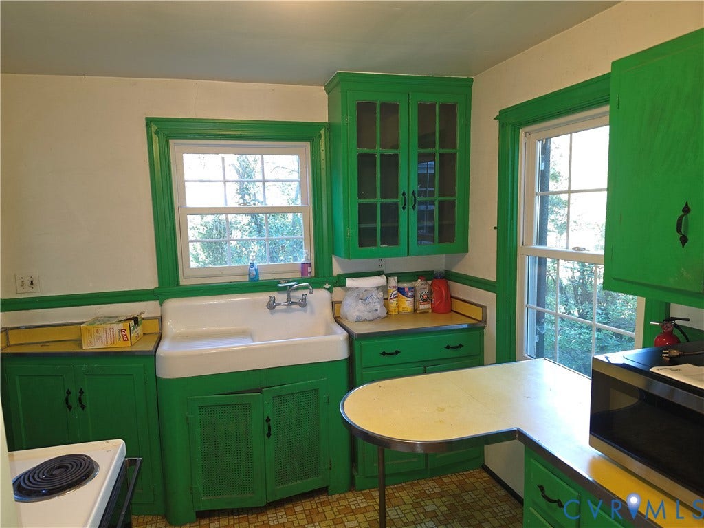 4114 Crestwood Road, Established, Richmond, VA 23227 Kitchen featuring a farmhouse-style apron sink, custom cabinetry with glass-front uppers, solid-surface countertops with integrated metal edging, and dual windows