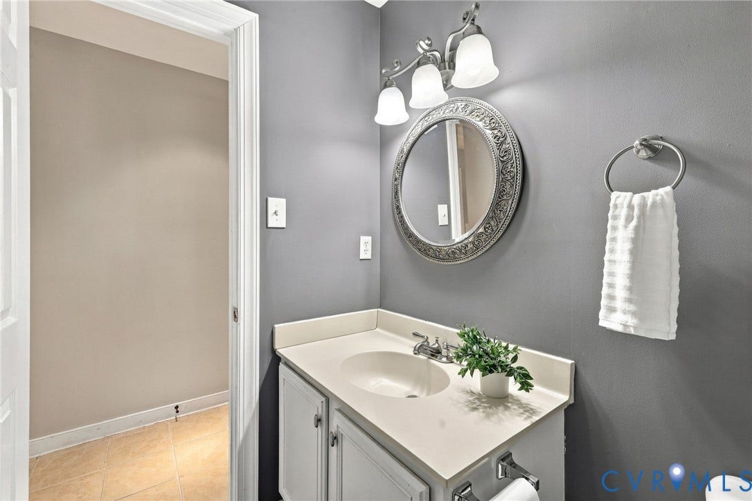 4712 Cedar Forest Road, Glen Allen, VA 23060 Main-level powder room featuring a single-sink vanity, decorative mirror, and updated light fixture.