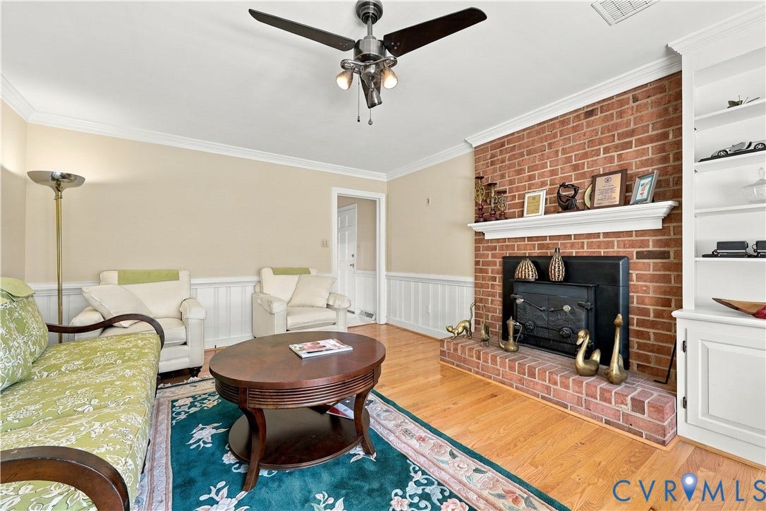 8307 Wallingford Lane, Chickahominy Bluffs, Henrico, VA 23227 Red brick fireplace with a wood-burning insert and mantel, built-in floor-to-ceiling shelving, wood-finish flooring, and crown molding