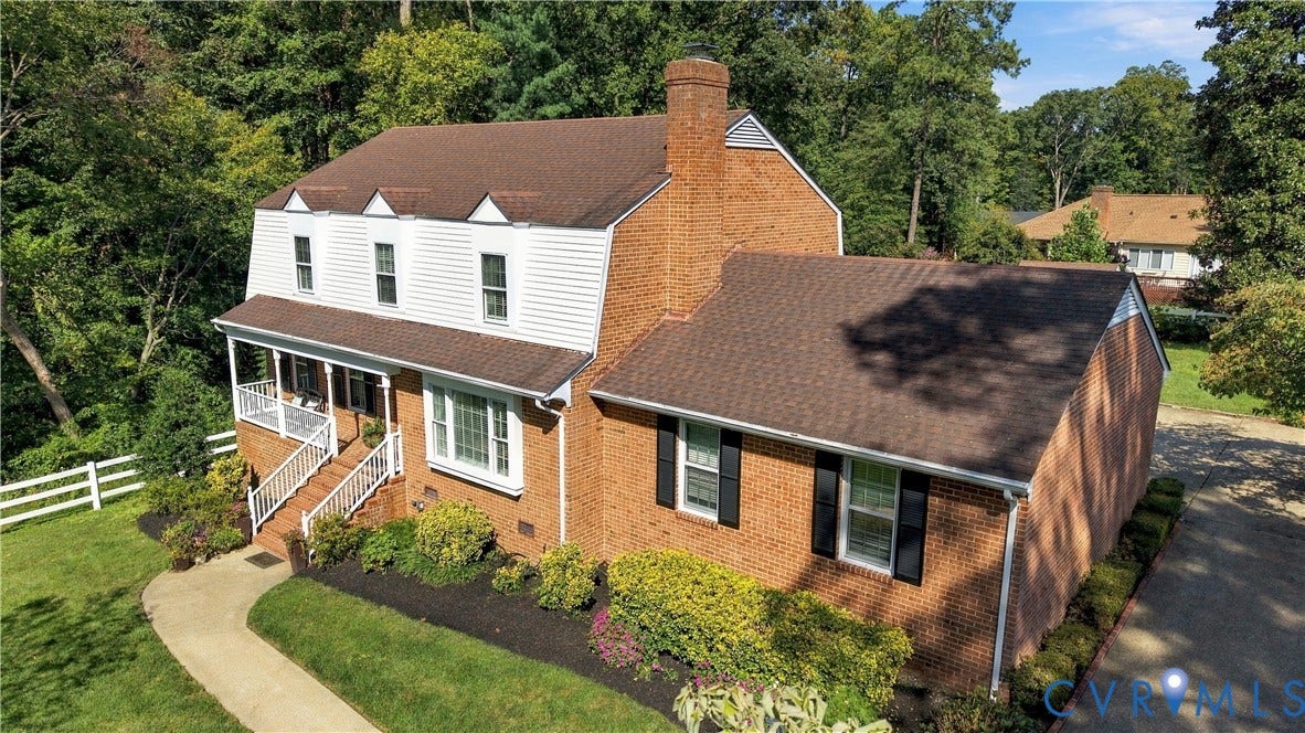 8307 Wallingford Lane, Chickahominy Bluffs, Henrico, VA 23227 Dutch Colonial exterior featuring red brick masonry, white vinyl siding, a multi-gabled roofline, a prominent brick chimney, and a covered front porch with white railing