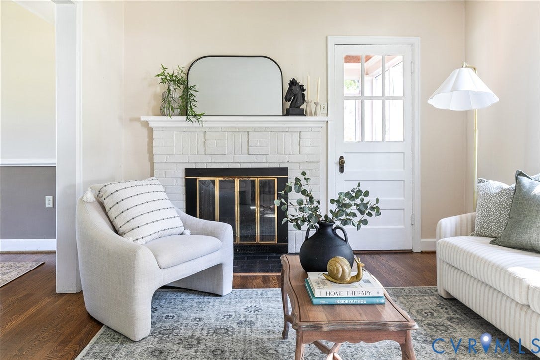 Painted brick fireplace with a decorative mantel, wood-finish flooring, and a multi-pane glass door