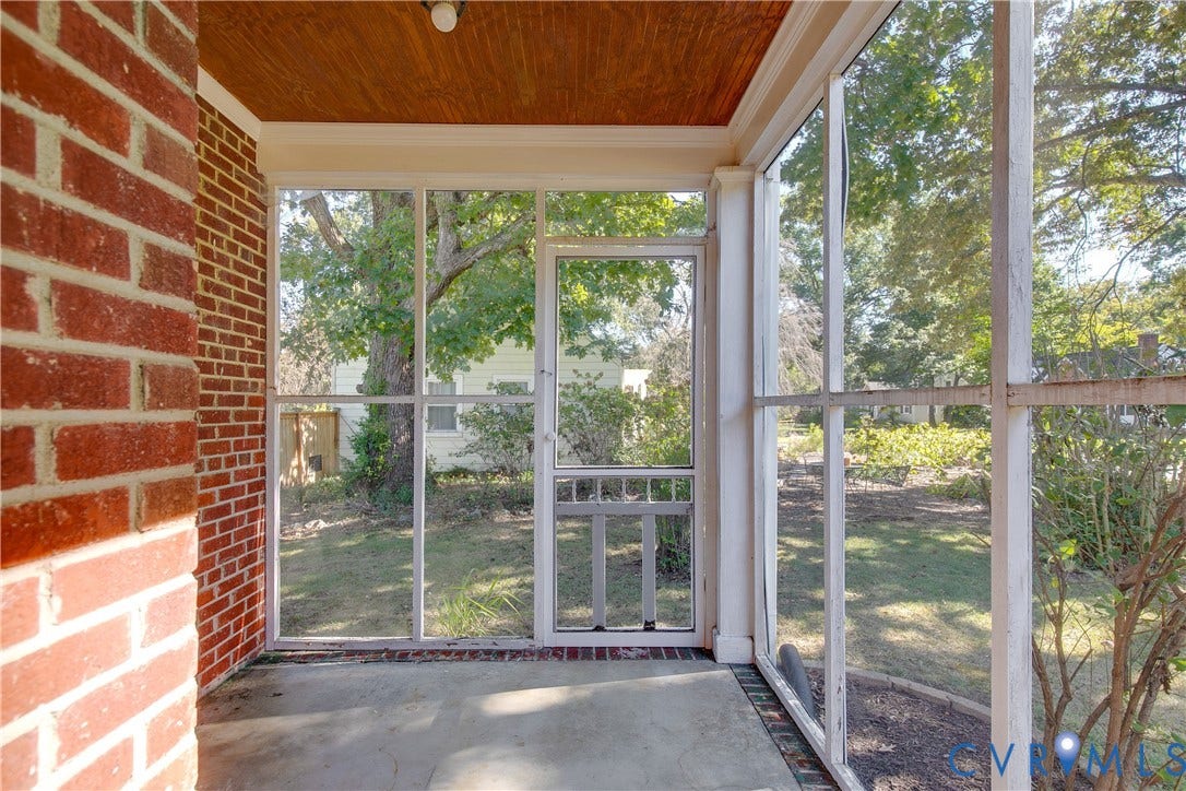 Screened-in porch featuring a red brick exterior wall, wood-paneled ceiling, concrete flooring