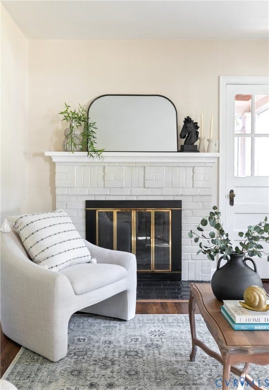 Painted white brick fireplace featuring a classic mantel, black metal firebox surround with brass trim, and a dark stone hearth