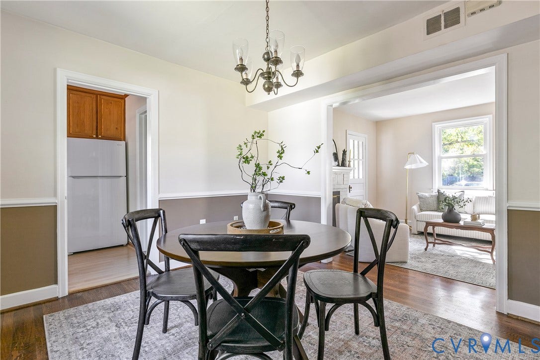 Dining area featuring wood-finish flooring, two-toned wall paint with chair rail molding, and a multi-arm chandelier