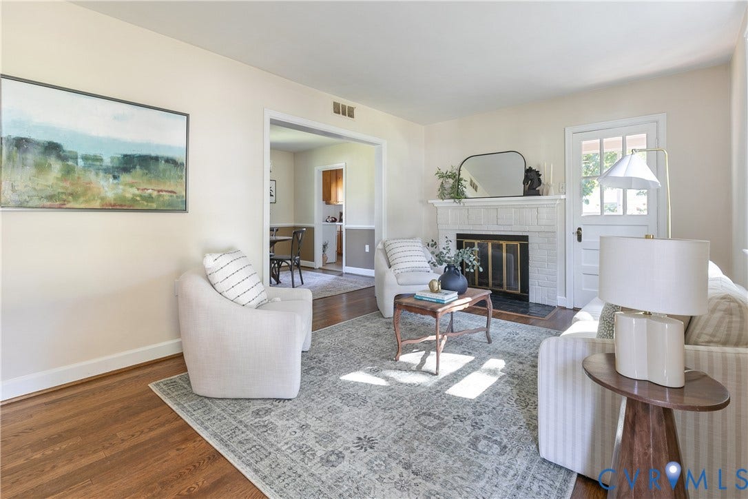 Living area featuring wood-finish flooring, a painted brick fireplace with a mantel, and a multi-lite glass panel door