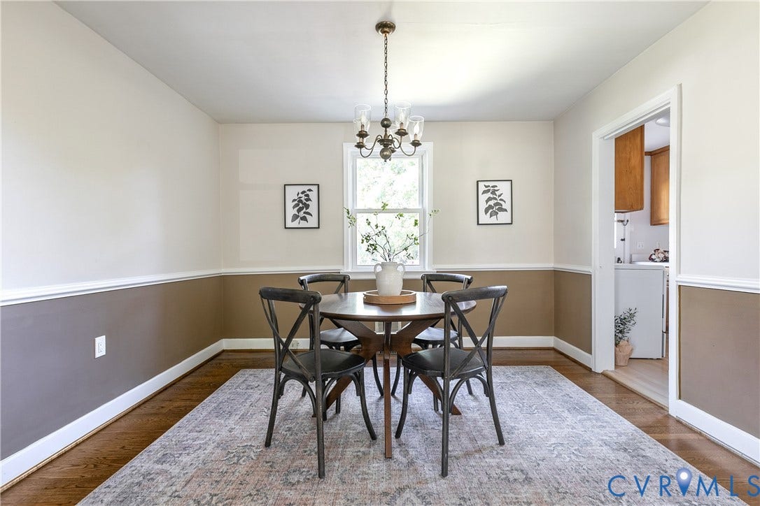 Dining area featuring wood-finish flooring, two-tone wall paint, chair rail molding, and a traditional multi-arm chandelier