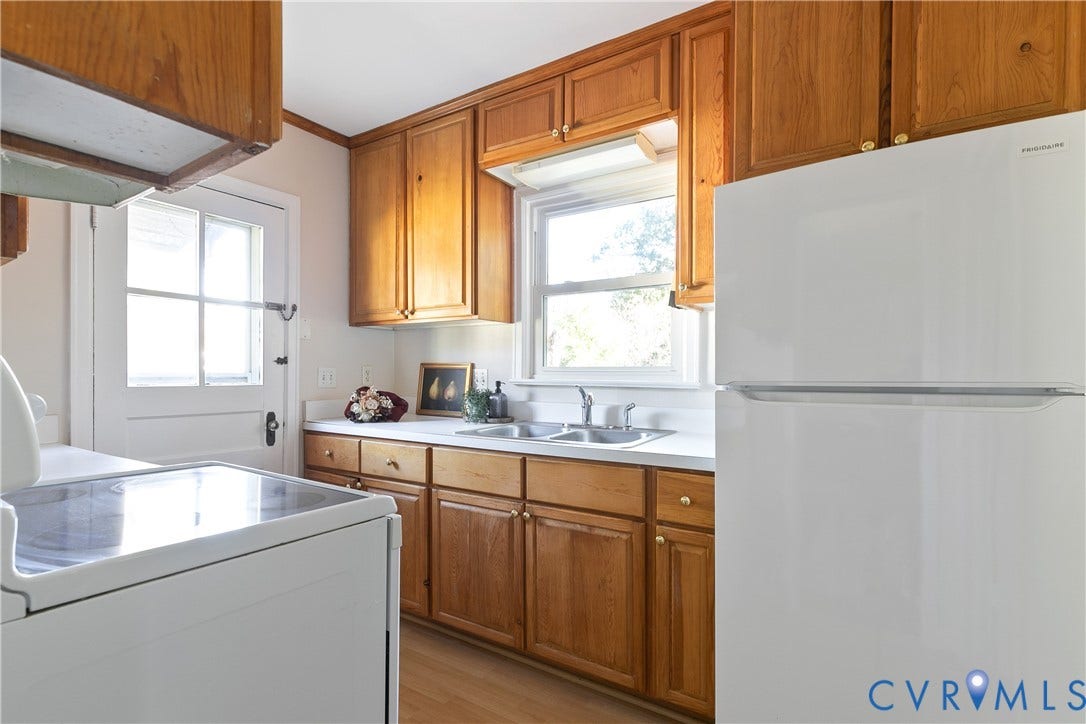 Kitchen featuring wood cabinetry, white appliances, a double-basin stainless steel sink, and a single-pane window above the counter