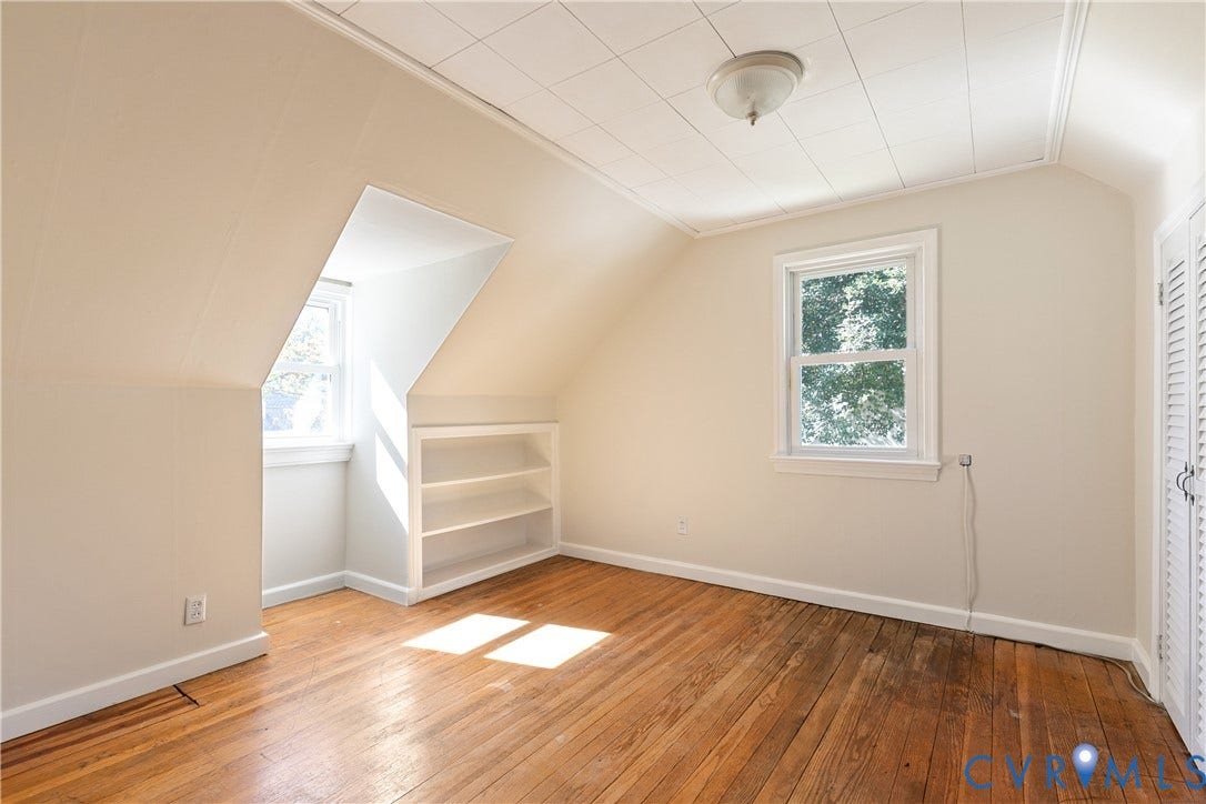 Room featuring wood-finish flooring, built-in recessed shelving, a dormer window, and a louvered-door closet