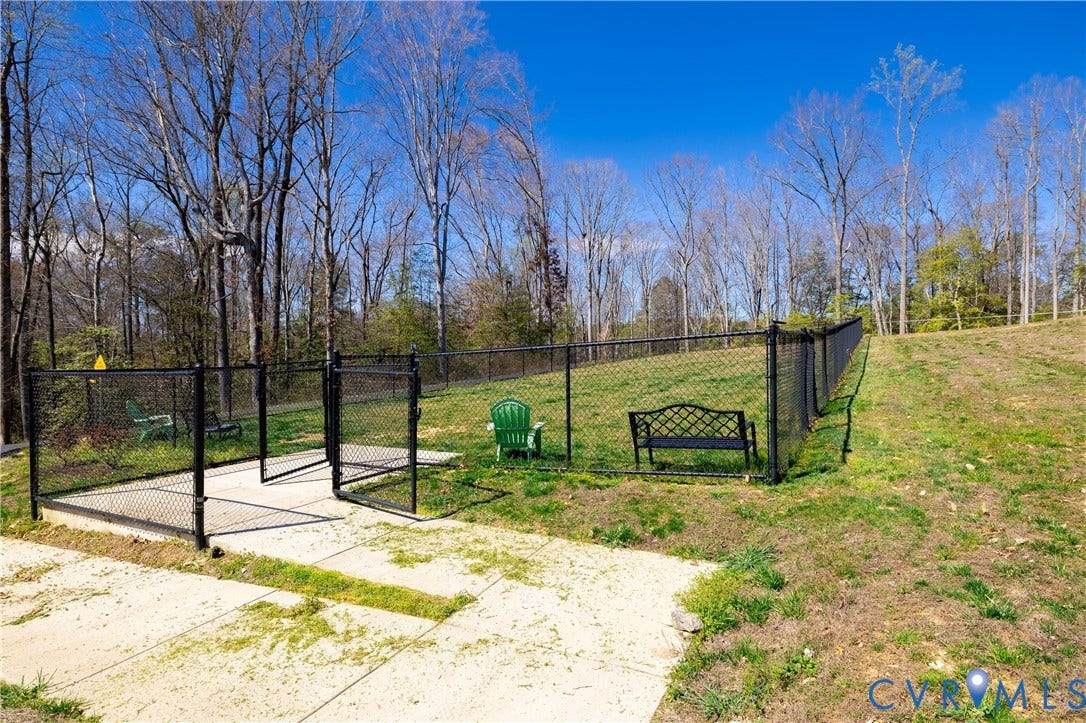 10525 Stony Bluff Drive, #107, Stony Run Condos, Ashland, VA 23005 Fenced outdoor area featuring a black chain-link perimeter, concrete landing, and wooded backdrop