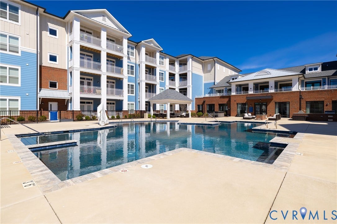 10525 Stony Bluff Drive, #107, Stony Run Condos, Ashland, VA 23005 Swimming pool featuring a paved deck, perimeter fencing, covered pavilion, and multi-story building exterior with brick and siding finishes