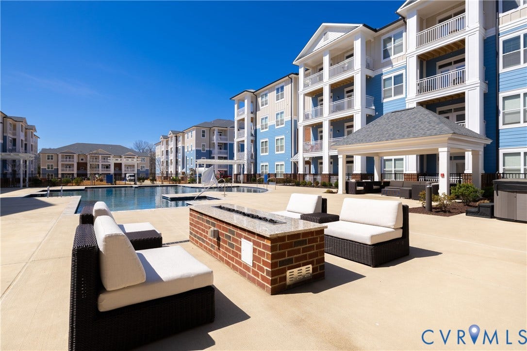 10525 Stony Bluff Drive, #107, Stony Run Condos, Ashland, VA 23005 Outdoor community space featuring a swimming pool, covered pavilion with columns, brick-constructed fire pit with a stone top, and expansive concrete decking