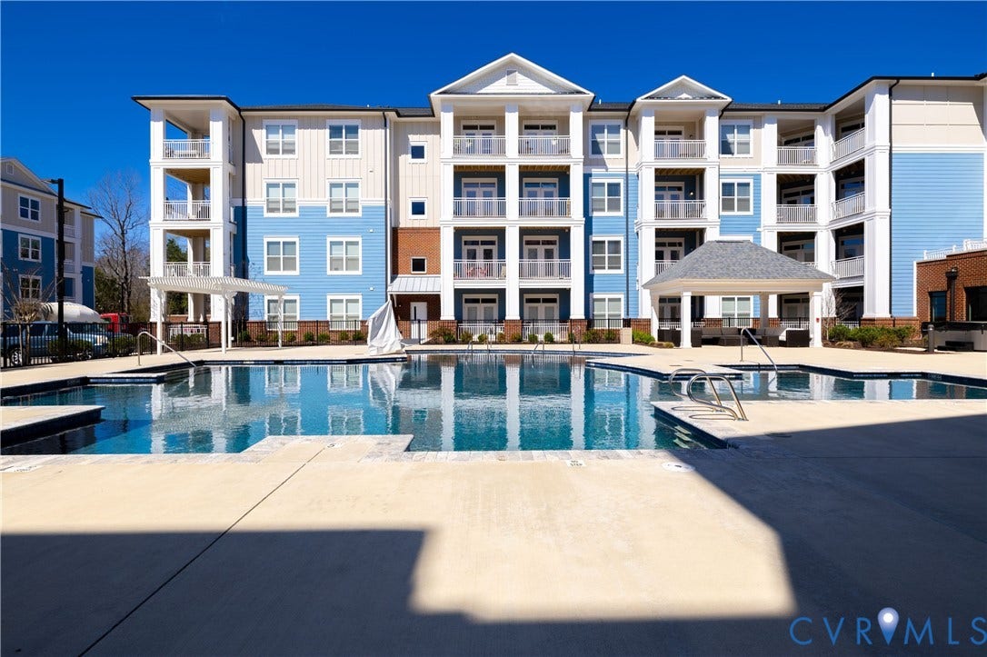 10525 Stony Bluff Drive, #107, Stony Run Condos, Ashland, VA 23005 Swimming pool with concrete decking, featuring a covered gazebo, structural columns, and multi-story building facade with private balconies