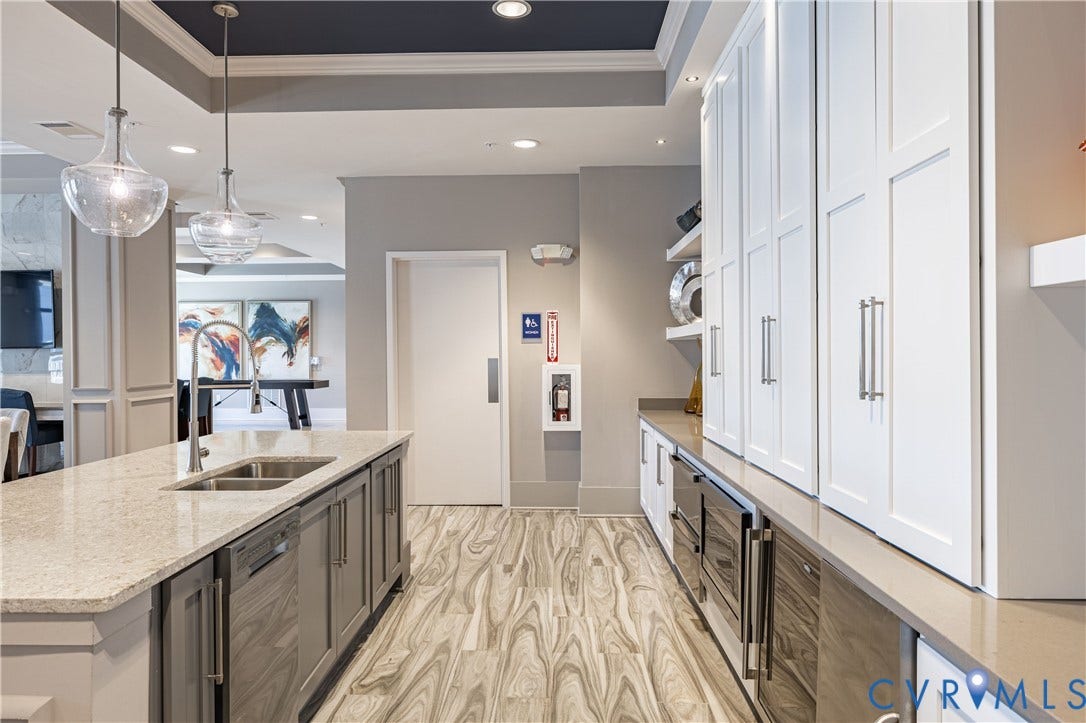 10525 Stony Bluff Drive, #107, Stony Run Condos, Ashland, VA 23005 Kitchen featuring a center island with a dual-basin sink, quartz countertops, floor-to-ceiling white cabinetry, wood-finish flooring, and glass pendant lighting