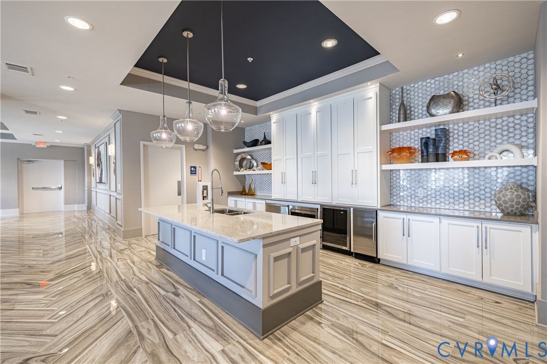 10525 Stony Bluff Drive, #107, Stony Run Condos, Ashland, VA 23005 Kitchen island featuring a stone countertop and undermount sink, complemented by white cabinetry, glass-tile backsplash, built-in stainless steel appliances, and large-format tile flooring