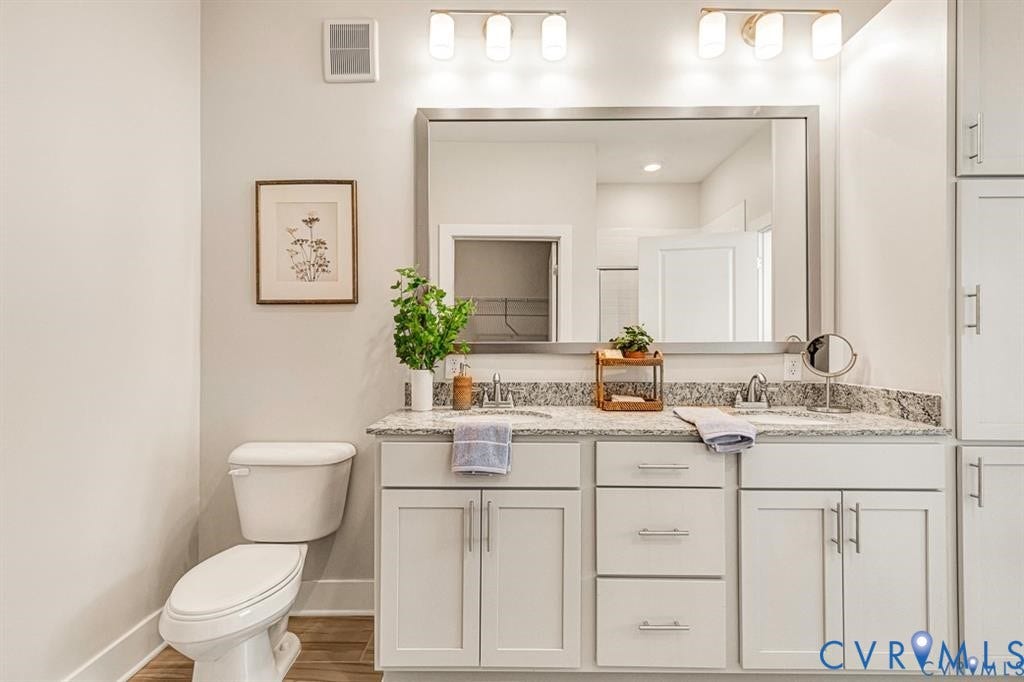 10525 Stony Bluff Drive, #107, Stony Run Condos, Ashland, VA 23005 Double vanity featuring light cabinetry, stone-finish countertops with dual undermount sinks, a large rectangular mirror, and dual wall-mounted light fixtures
