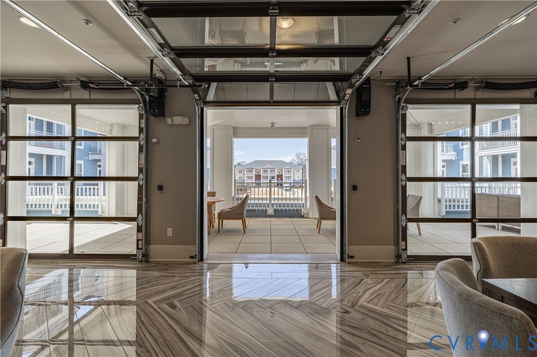 10525 Stony Bluff Drive, #107, Stony Run Condos, Ashland, VA 23005 Open-concept space featuring retractable glass garage-style doors, high-gloss stone-finish flooring in a chevron pattern, and an exterior balcony with tile surfacing