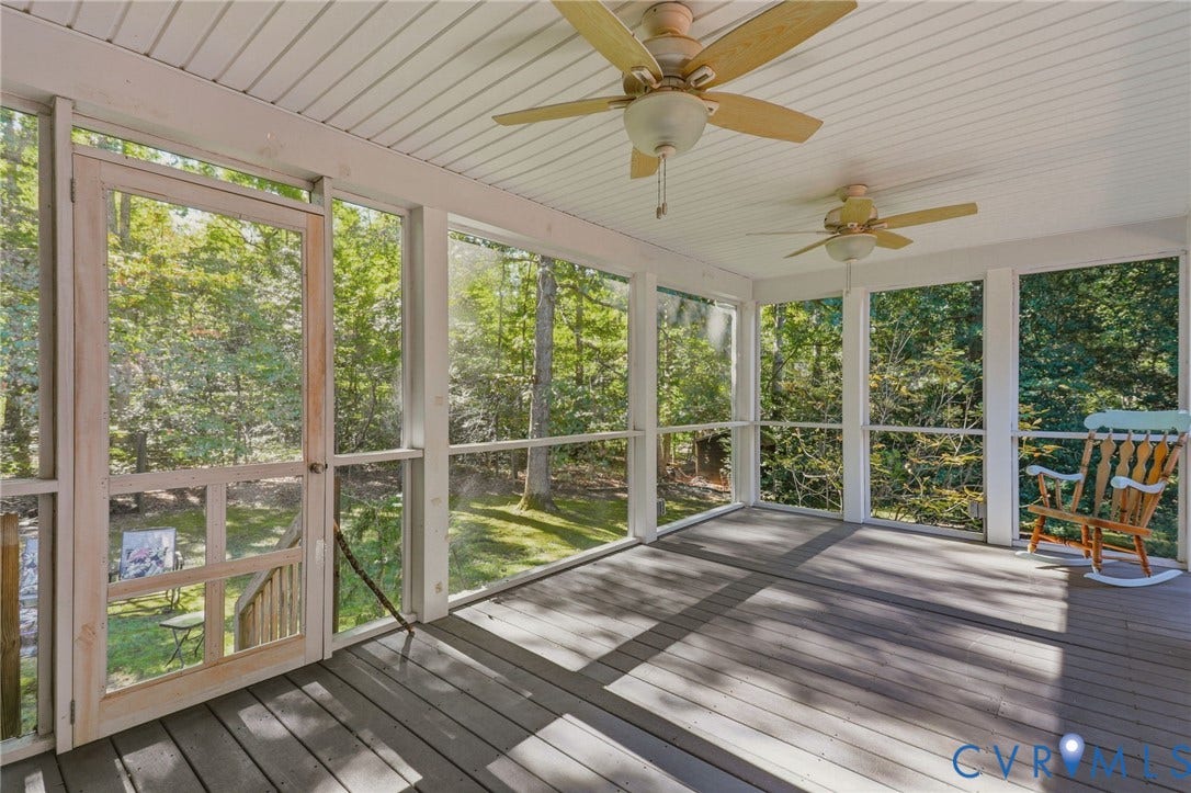 Screened-in porch featuring wood-plank decking, beadboard ceiling, dual ceiling fans, and wood-framed screen door