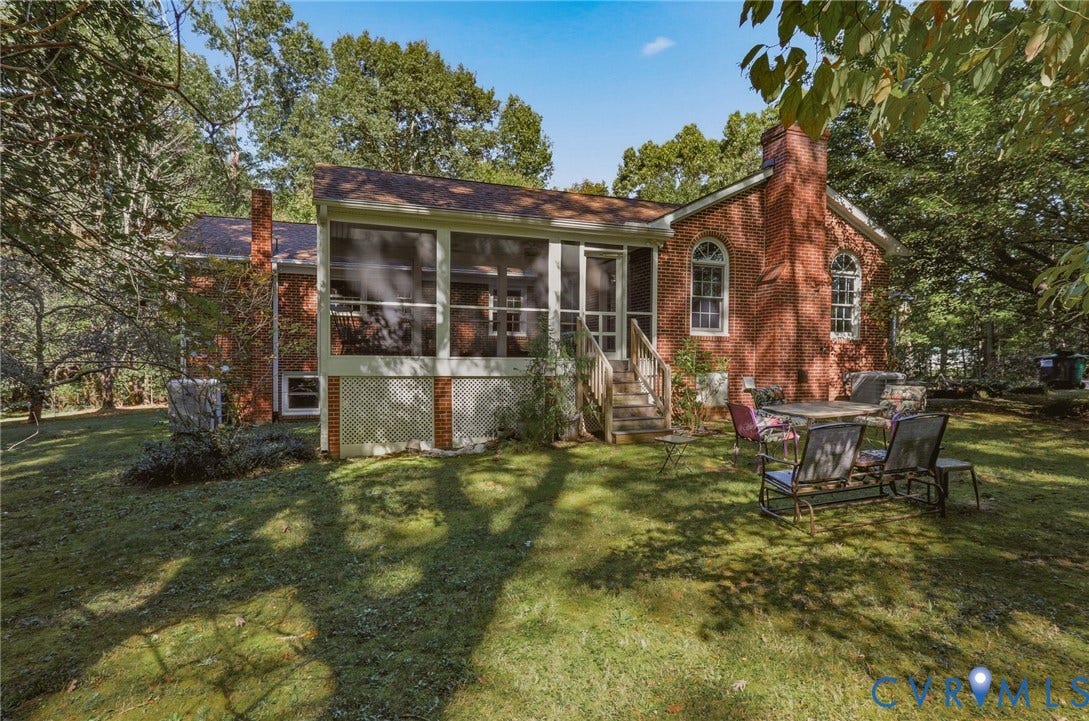 Brick exterior residence featuring a screened porch, elevated wooden staircase, exterior chimney, and arched window detailing