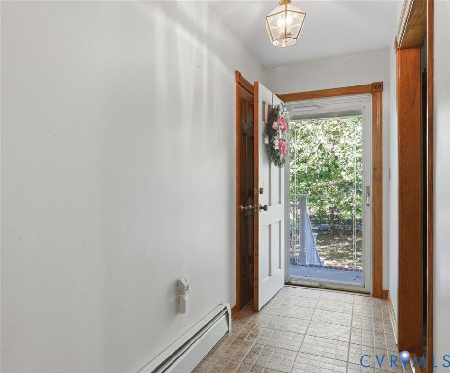 Entryway featuring tiled flooring, natural wood trim, a paneled door, and a glass-paneled storm door