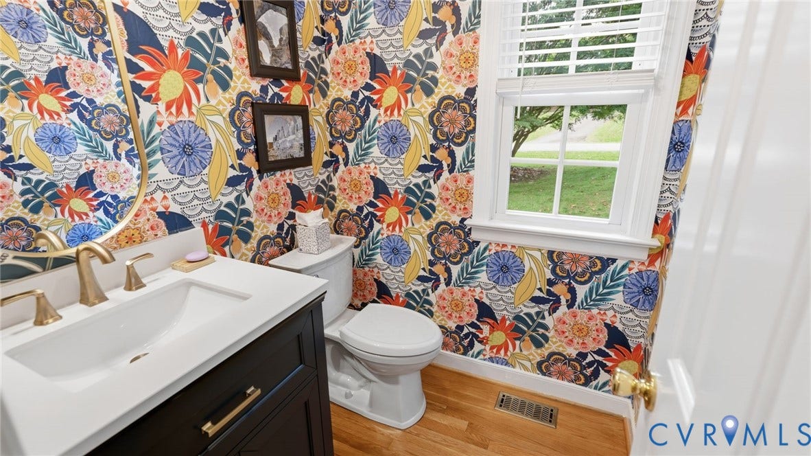 2040 Normandstone Drive, Roxshire, Midlothian, VA 23113 Powder room featuring floral wallpaper, wood-finish flooring, dark-finish cabinetry with a white countertop, and gold-tone fixtures