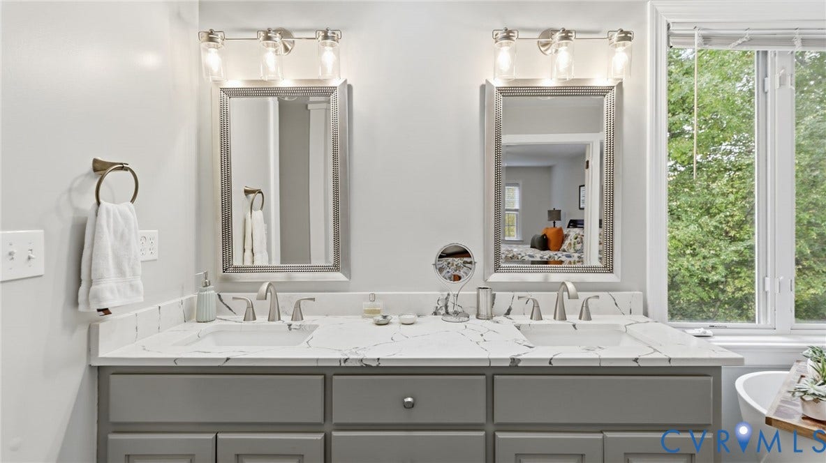 2040 Normandstone Drive, Roxshire, Midlothian, VA 23113 Dual-sink vanity featuring a stone-composite countertop with integrated basins, grey cabinetry, framed wall mirrors, and multi-bulb light fixtures