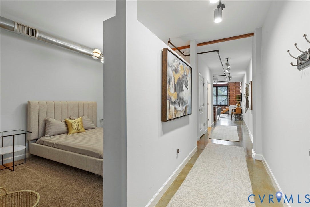 815 Porter Street, #U301, Richmond, VA 23224 Industrial-style interior featuring exposed metallic ductwork, concrete flooring, exposed ceiling-mounted piping, adjustable track lighting, and a partial-height partition wall