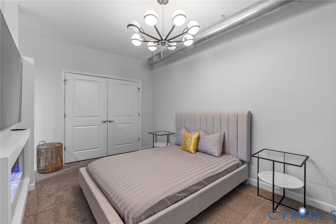 815 Porter Street, #U301, Richmond, VA 23224 Industrial-style space featuring an exposed metal duct, contemporary multi-arm orb chandelier, built-in electric fireplace, and double-door closet