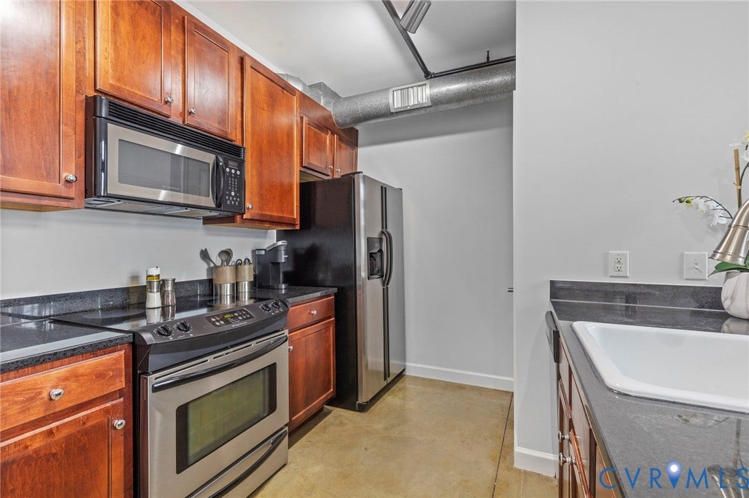 815 Porter Street, #U301, Richmond, VA 23224 Kitchen featuring stained wood cabinetry, dark stone-style countertops, stainless steel appliances, and polished concrete flooring