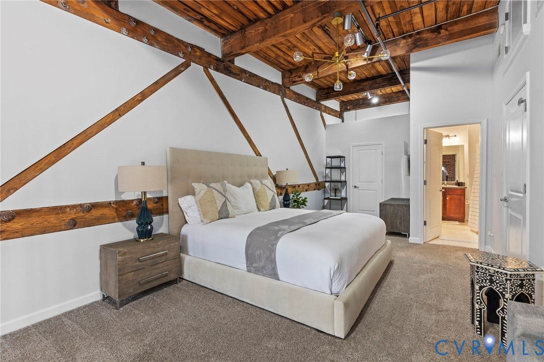 815 Porter Street, #U301, Richmond, VA 23224 Exposed wood ceiling beams, decorative structural wall bracing, high ceilings, brass-finish chandelier, and neutral wall-to-wall carpeting